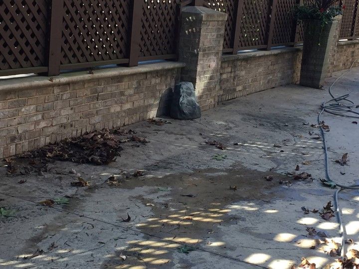 A brick wall and a concrete floor with leaves on it