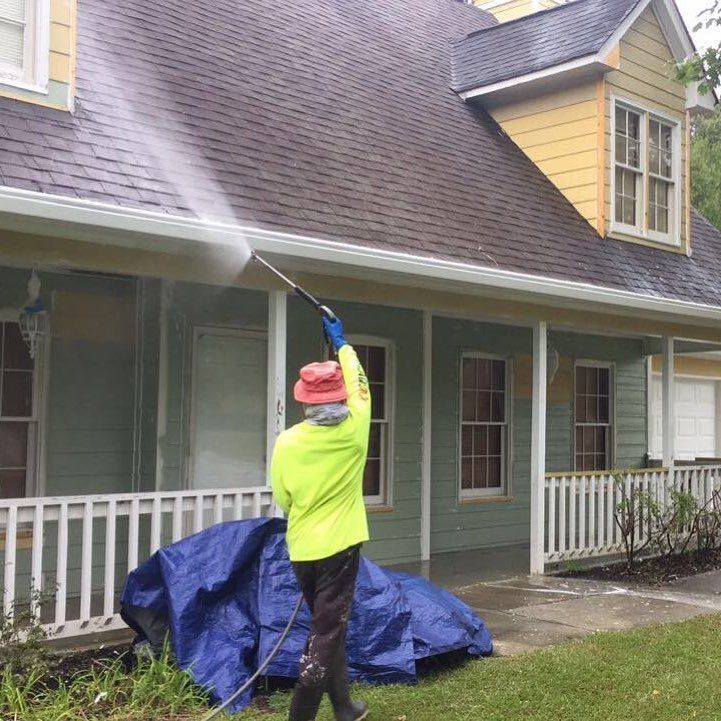 A man is spraying water on the roof of a house