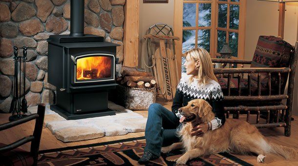 Woman and dog sitting next to large wooden stove — Freehold, NJ — Fireside Pros