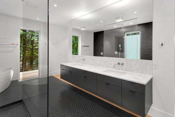 Beautiful modern bathroom interior in new luxury home with double vanity, mirror, and cabinets