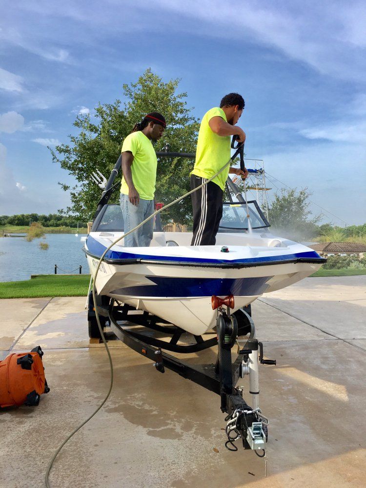 Two men are washing a boat in a driveway