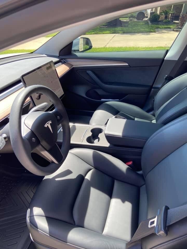 The interior of a tesla model 3 with a steering wheel and seats.