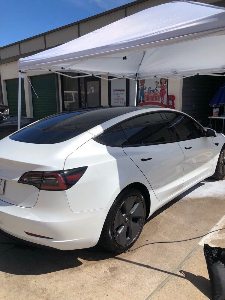 A white tesla model 3 is parked under a white tent