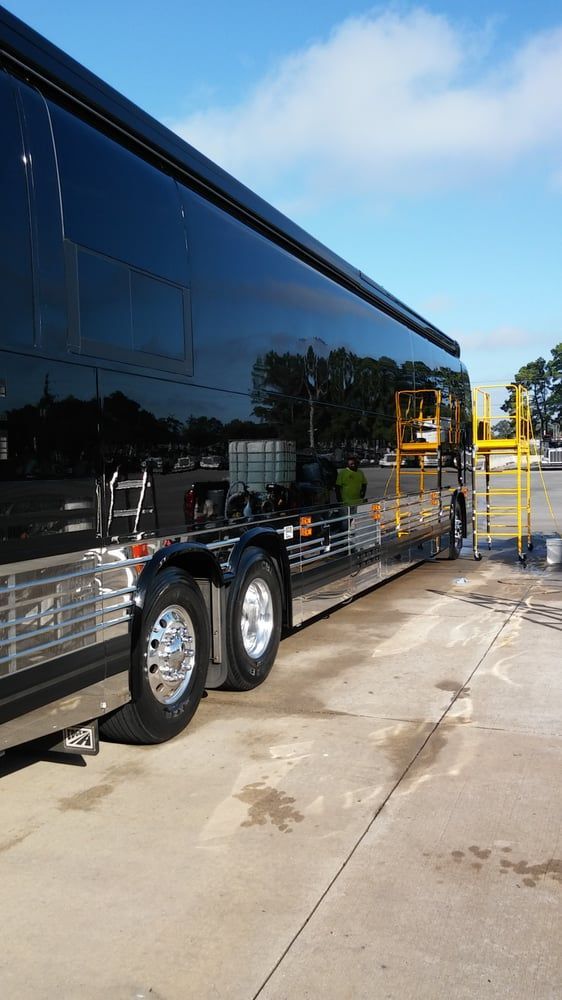 A large black bus is parked in a parking lot