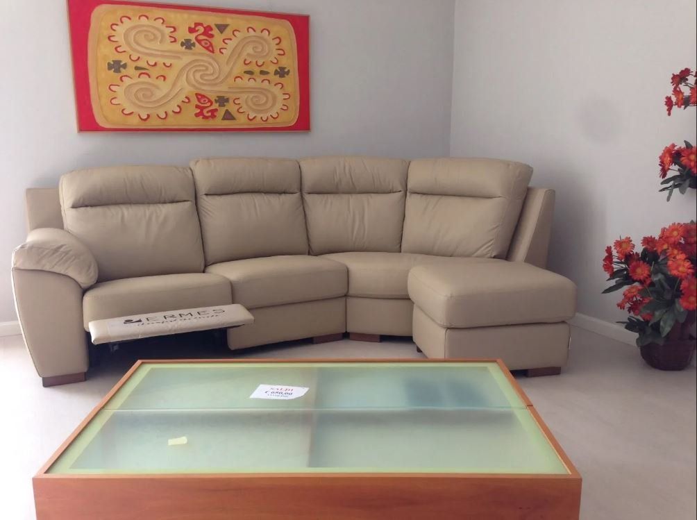 Divano componibile beige in un soggiorno, con un tavolino da caffè e opere d'arte colorate sulla parete.