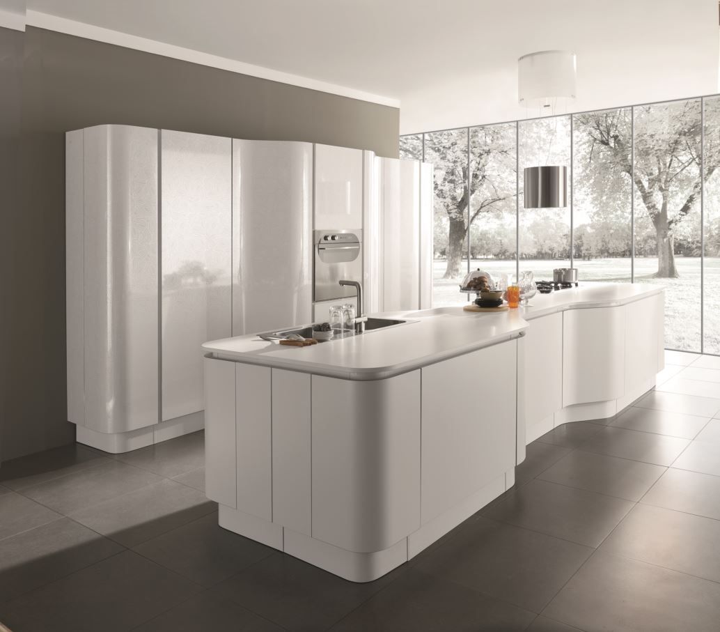 Moderna cucina bianca con mobili curvi e isola, ampie finestre con vista invernale.