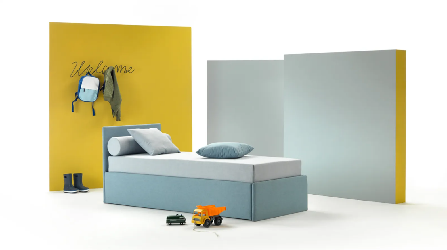 Letto blu nella cameretta di un bambino con parete gialla, zaino e camion giocattolo.
