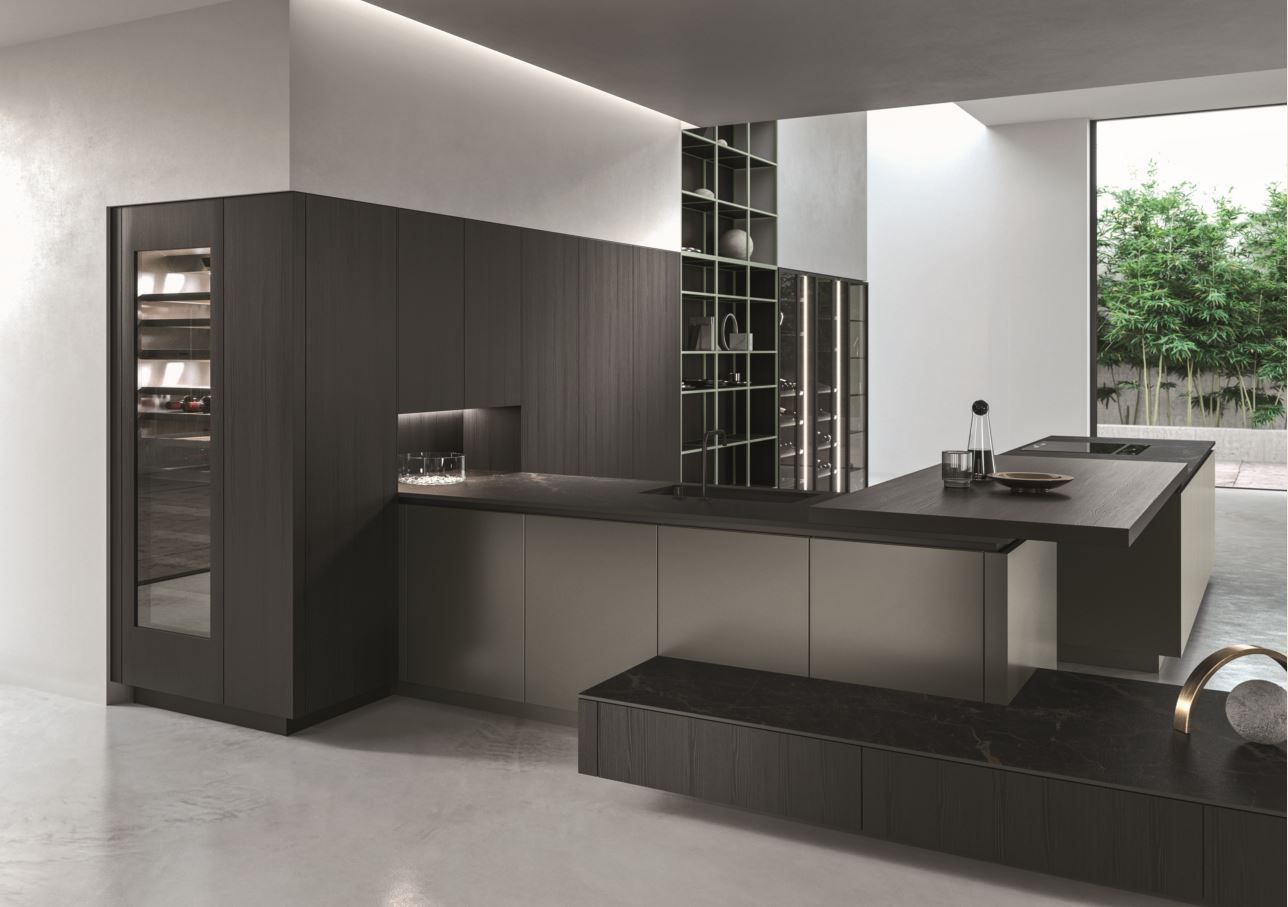 Cucina moderna con mobili scuri, cantinetta per il vino e bancone a isola con vista sul verde.