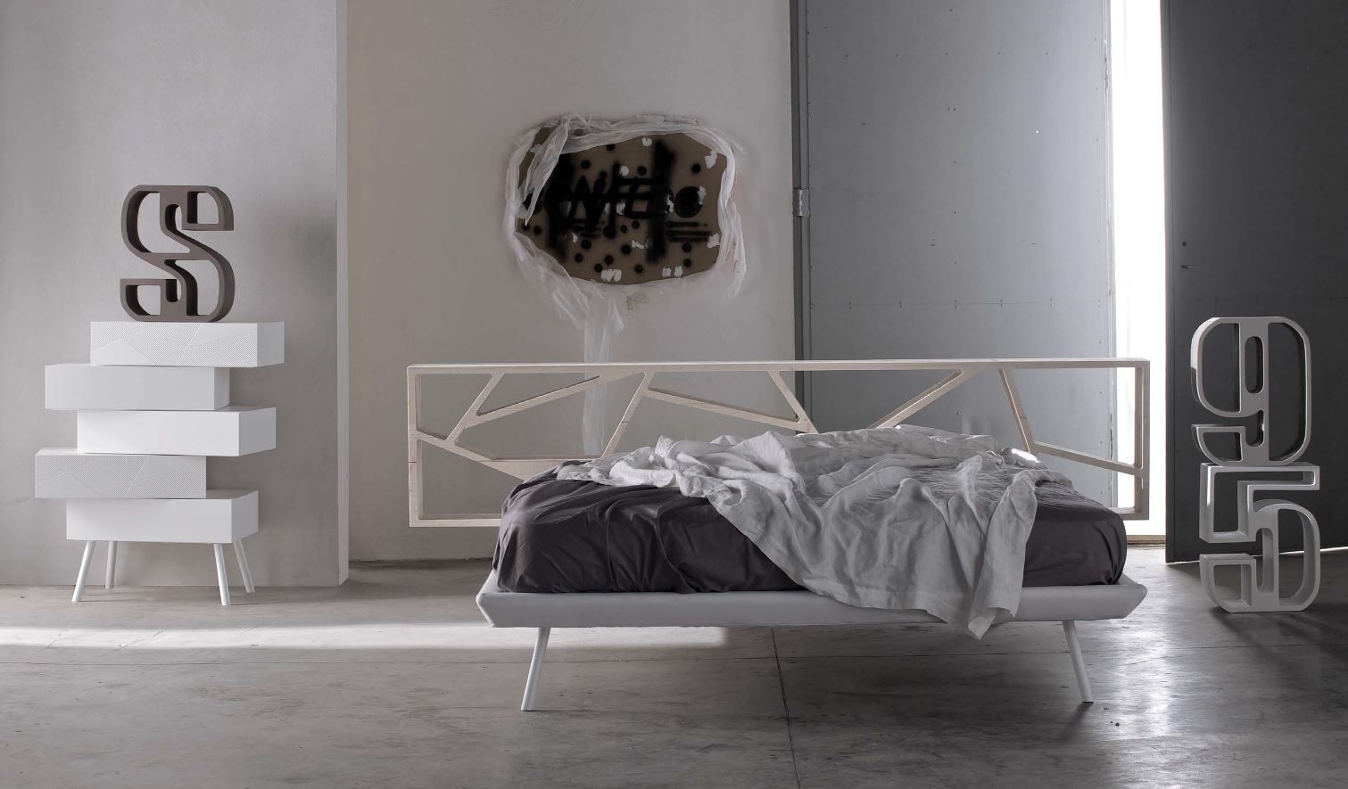 Camera da letto moderna con struttura del letto bianca, opere d'arte astratte e contenitori impilati.