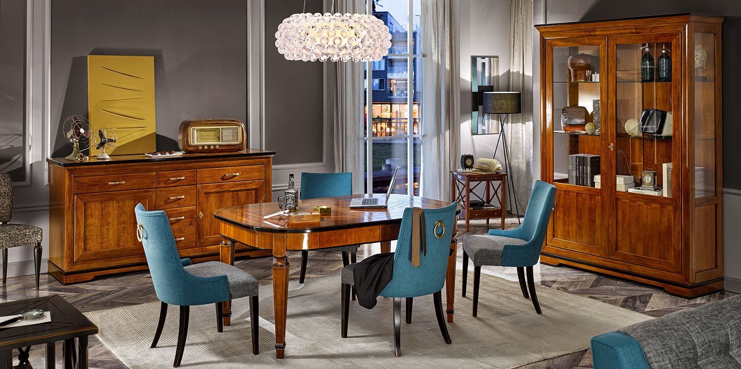 Una sala da pranzo con mobili in legno e sedie imbottite blu, illuminata da un lampadario.