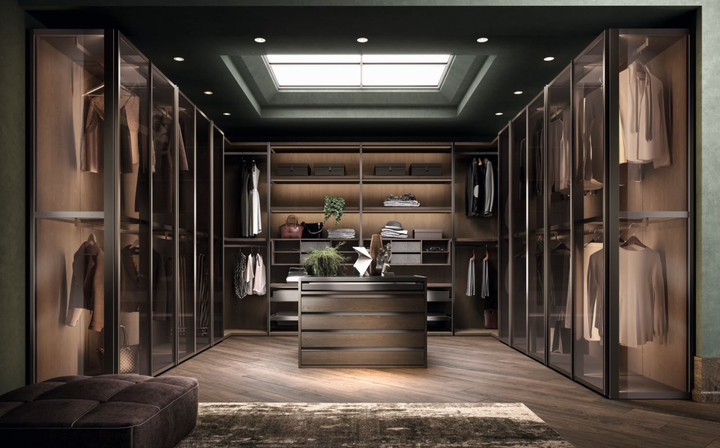 Cabina armadio con ripiani in legno scuro, porte in vetro e isola centrale. Pareti verde smeraldo, lucernario sopra la testa.