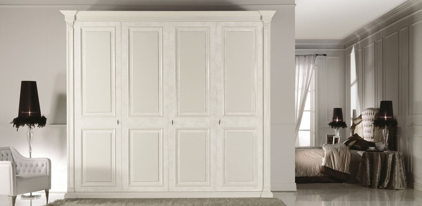 Armadio color crema a quattro ante in una stanza con lampada, sedia e tavolo.