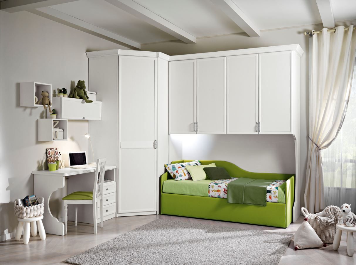 Una cameretta bianca per bambini con un divano letto verde, una scrivania e un mobiletto angolare.