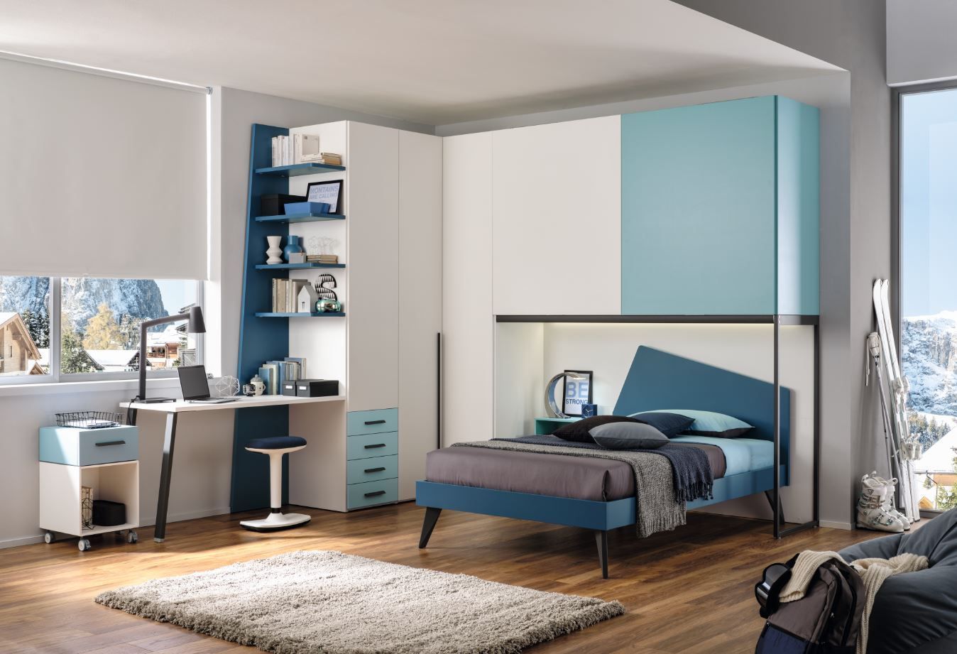 Camera da letto moderna con letto, scrivania, spazio per riporre gli oggetti e vista sulle montagne innevate.