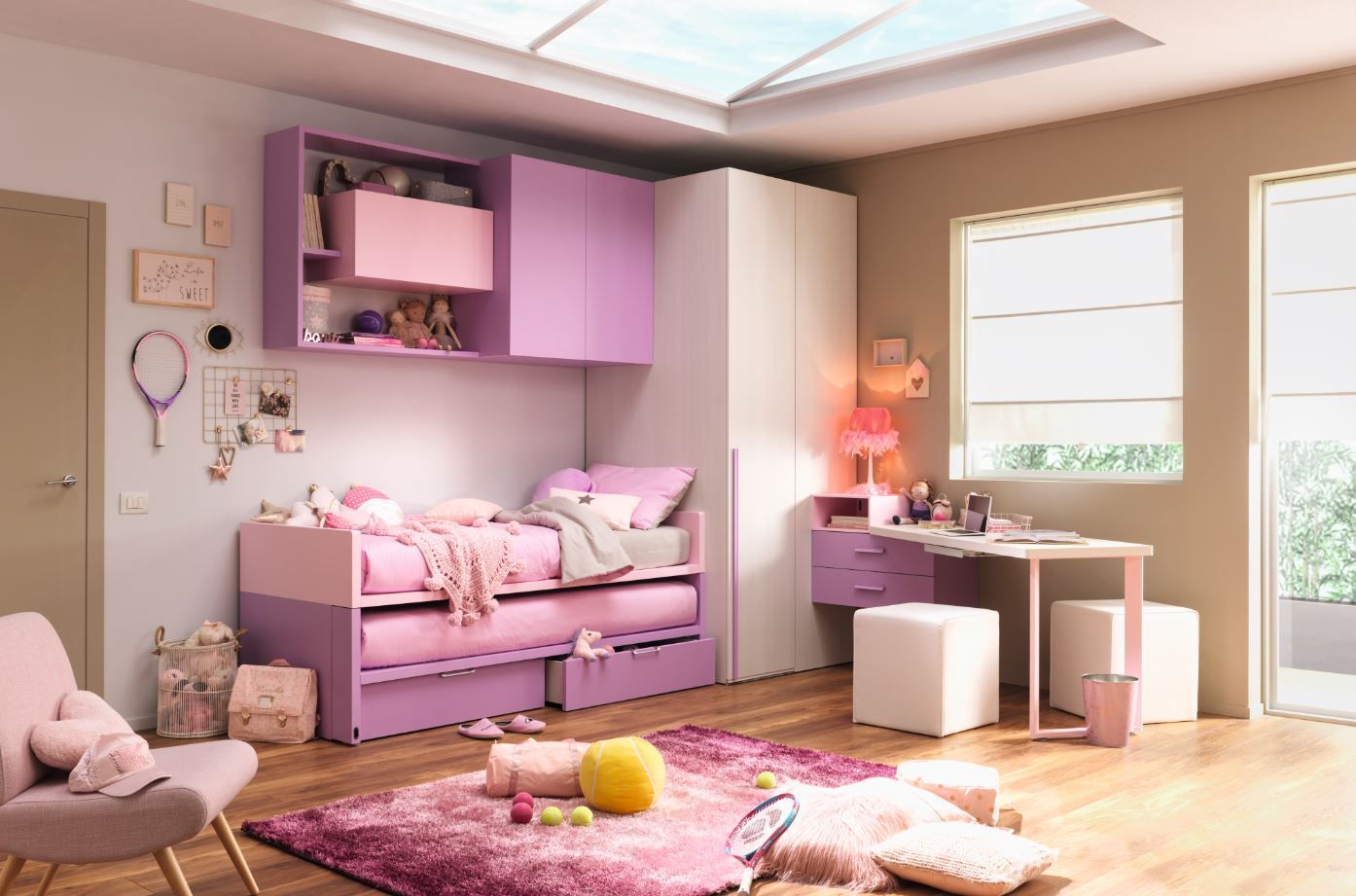 Camera da letto per bambina con mobili rosa e viola, un letto, una scrivania e un lucernario.