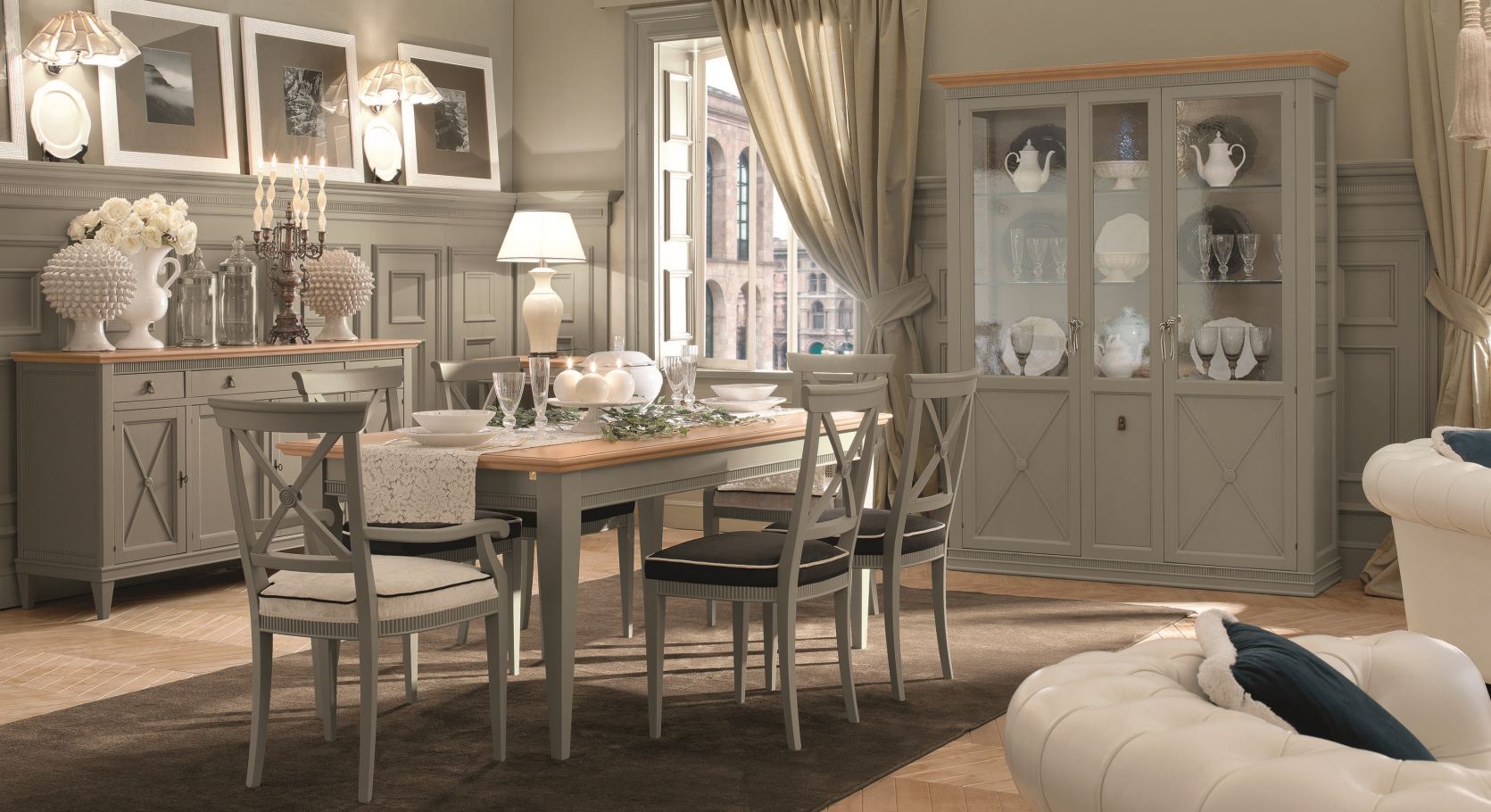 Elegante sala da pranzo con mobili grigi, lampadario e vista attraverso una finestra.