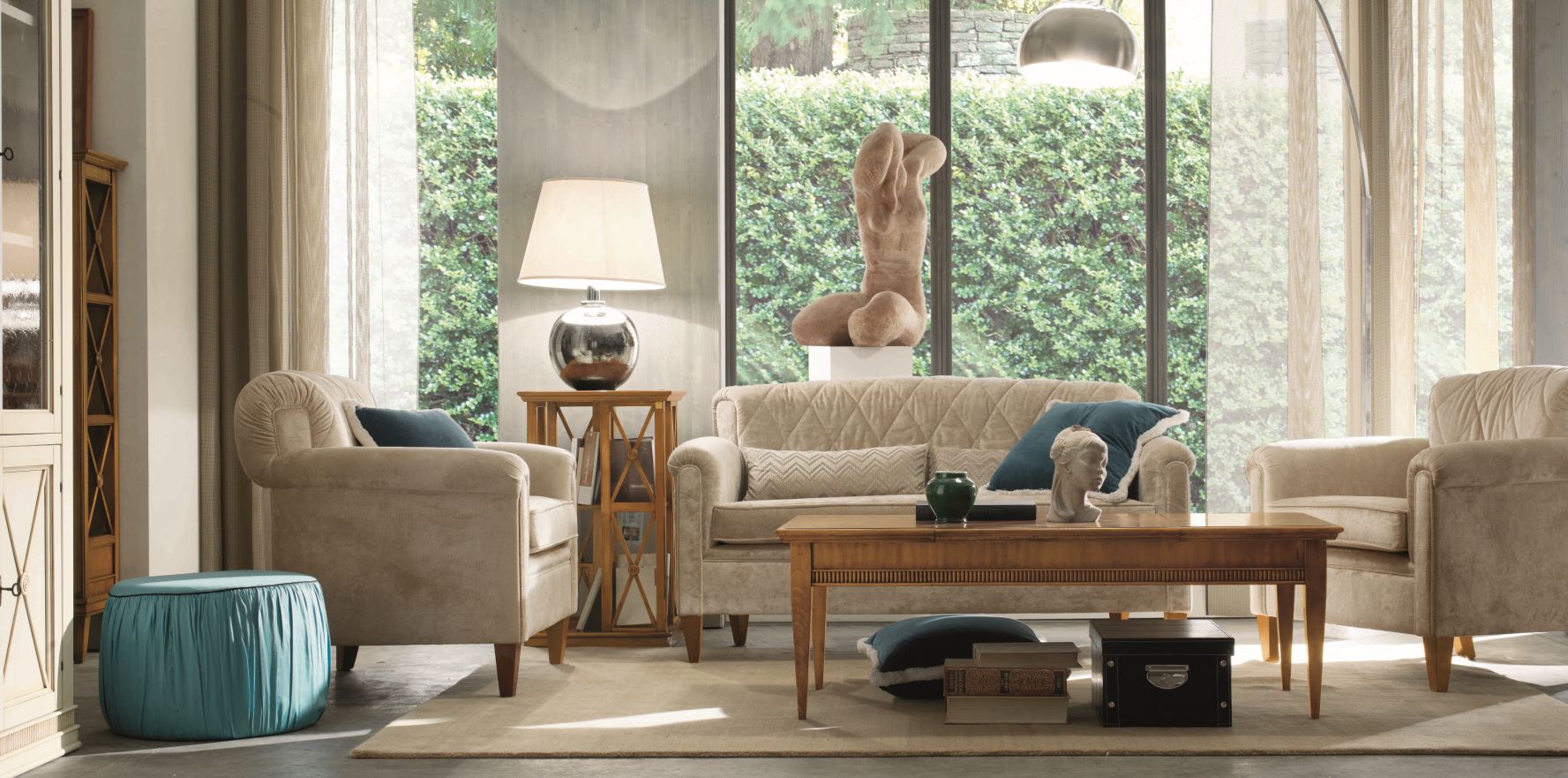 Soggiorno con divano, poltrone, tavolino, sculture e grande finestra.