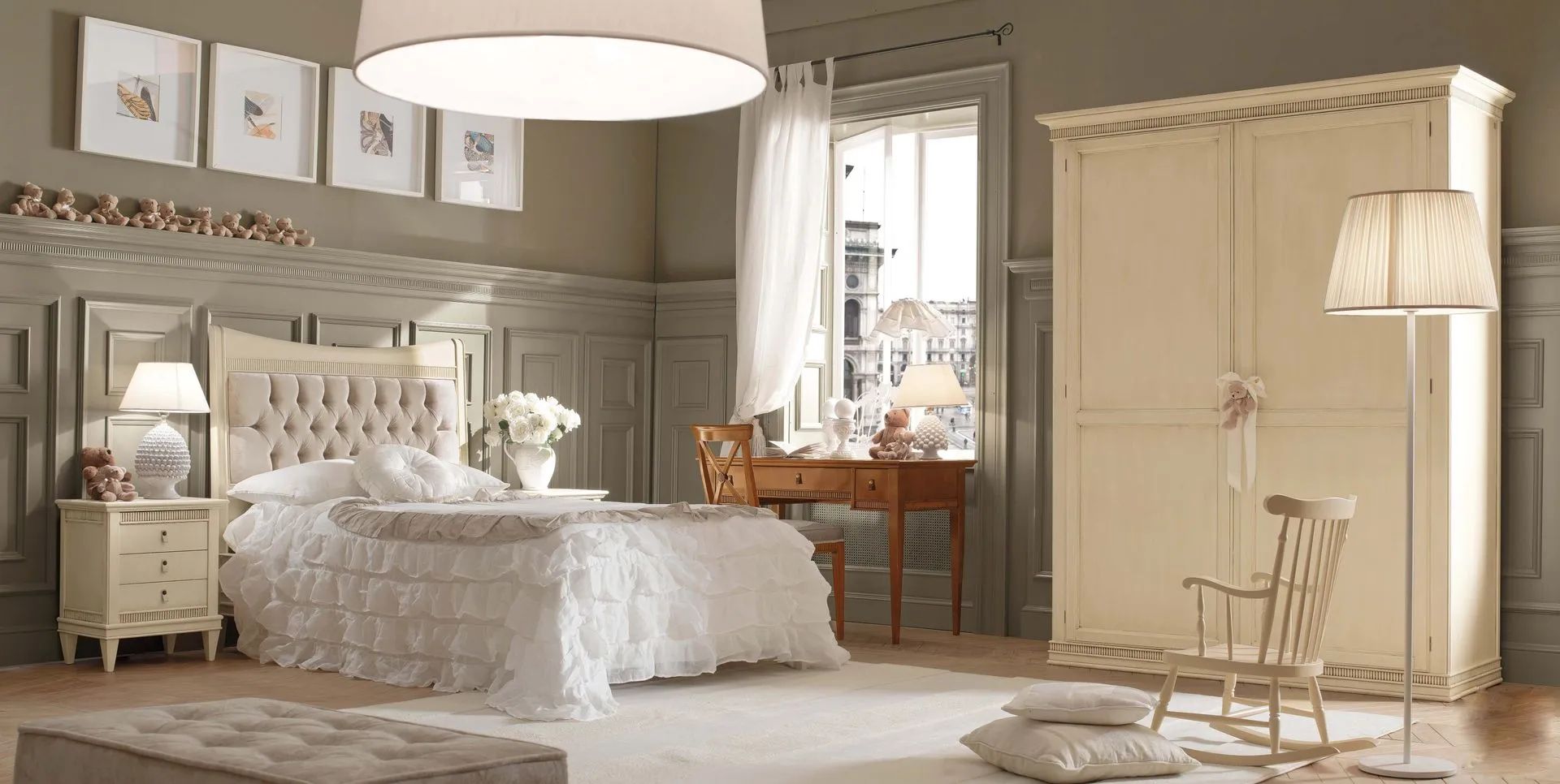 Camera da letto con mobili bianchi e beige, tra cui un letto, un comodino, un armadio e una sedia a dondolo.