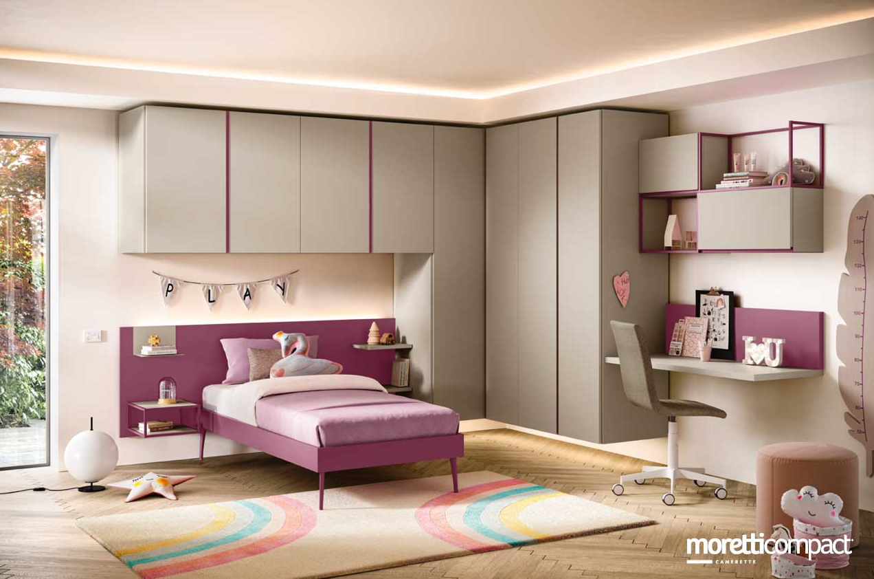 Cameretta per bambini viola e grigia con letto, scrivania, armadietti e tappeto arcobaleno.