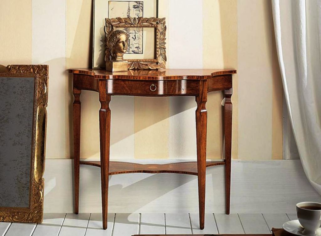 Consolle decorata color crema con due cassetti, un ripiano e gambe curve. Specchio e decorazioni alla parete.