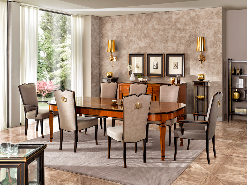 Sala da pranzo formale con mobili in legno, sedie color crema, grande tavolo e buffet contro una parete decorata.