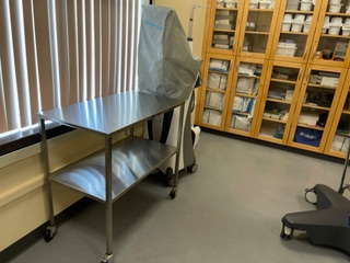 A stainless steel table is in a room with a lot of cabinets