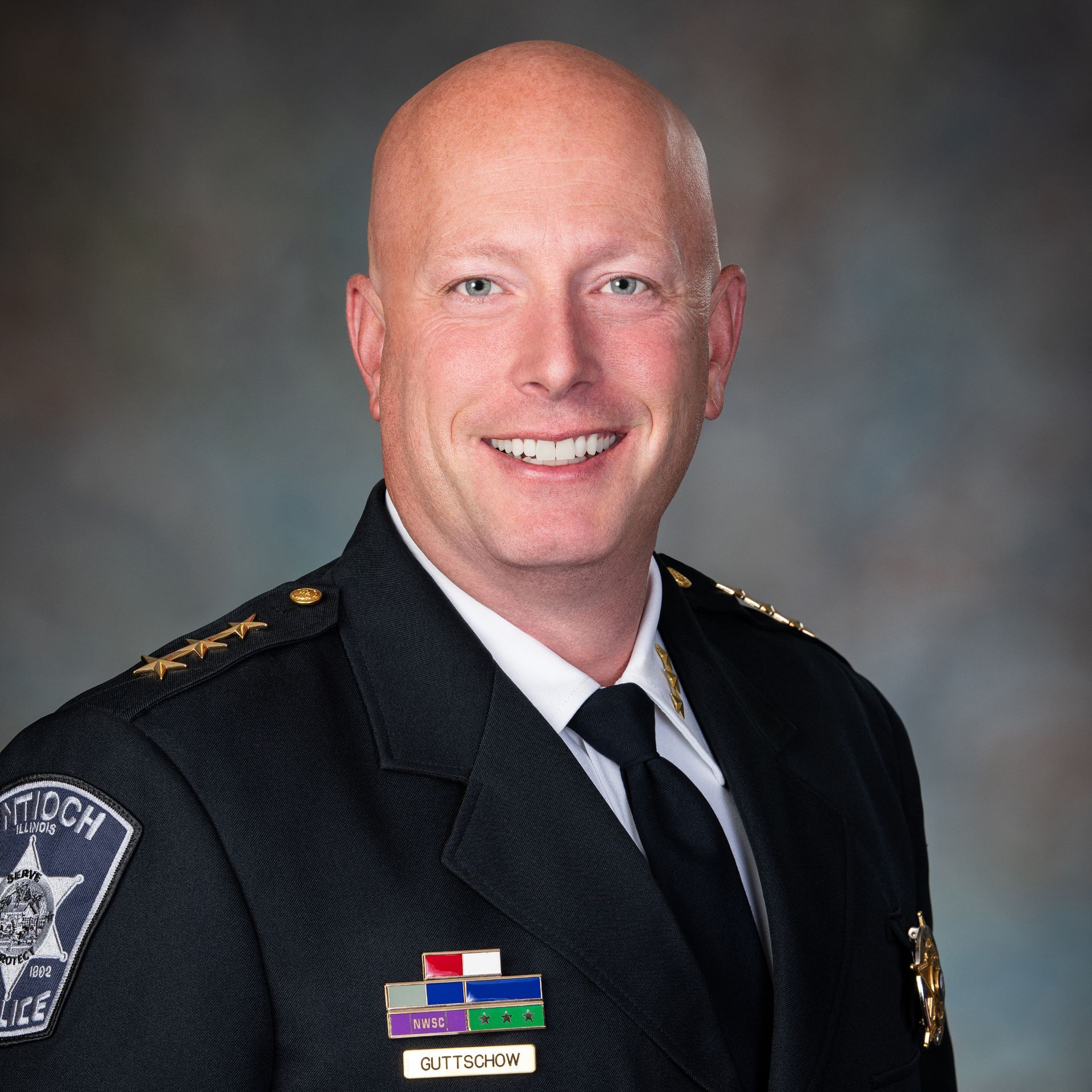 Police Chief with a bald head, in uniform, smiling at the camera.