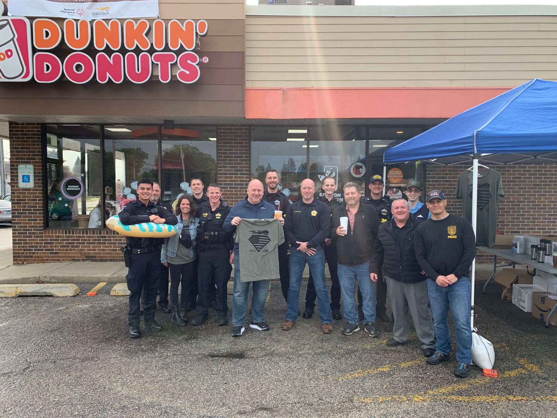 Police officers and supporters gather at Dunkin' Donuts, posing for photo under a tent.