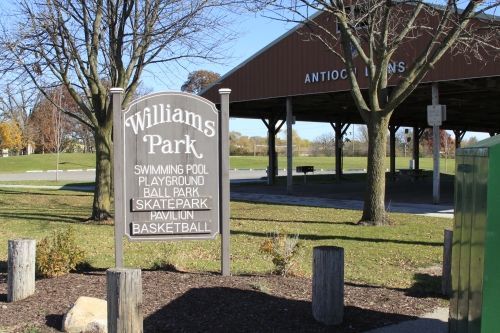 Sign for Williams Park with amenities listed; pavilion in background.