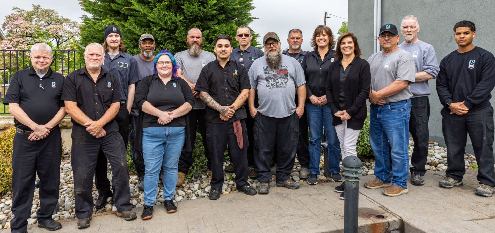 Group of people standing outside, posing. Some wear black shirts and jeans.