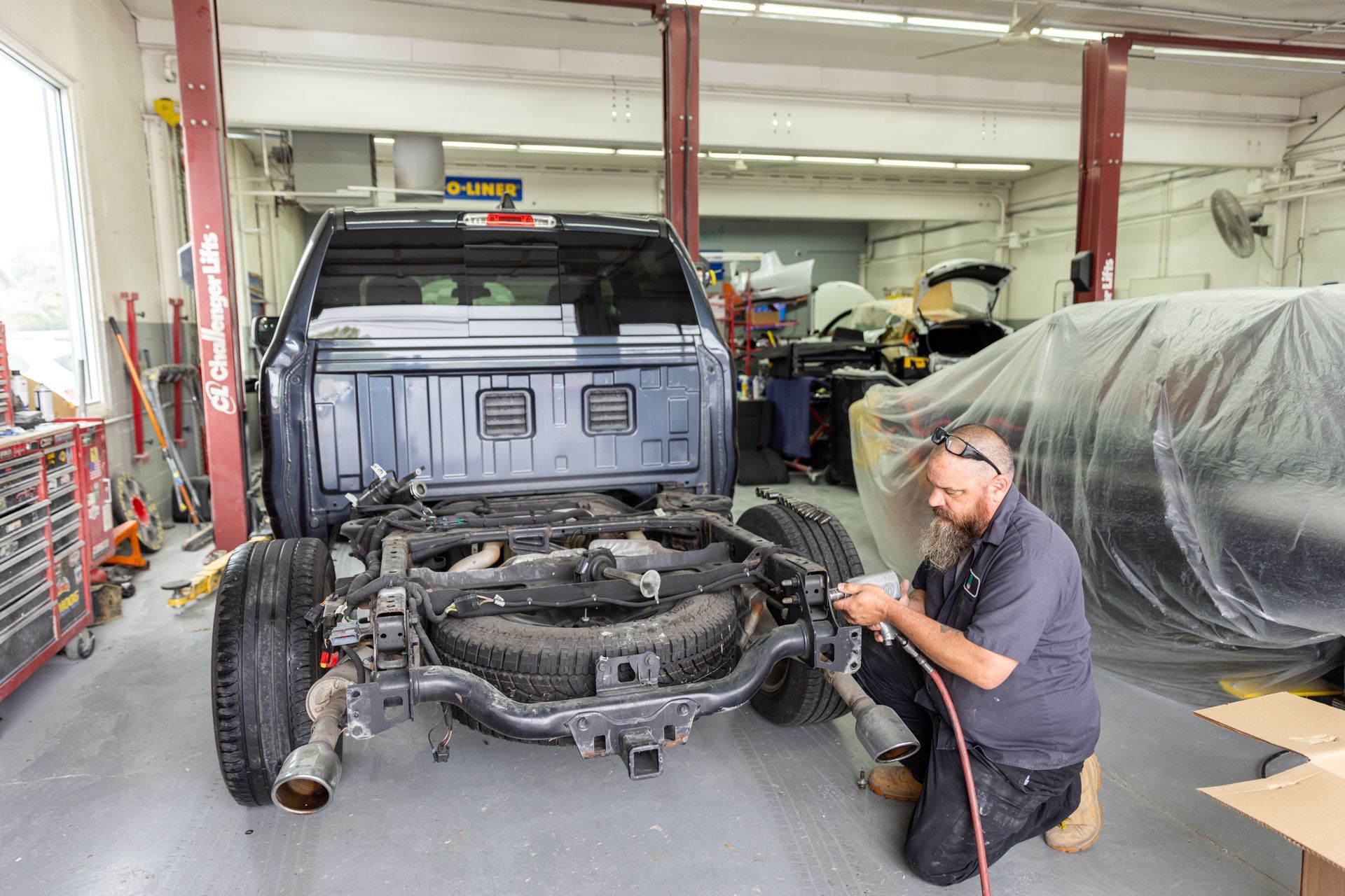 Mechanic working on a truck frame in a repair shop.