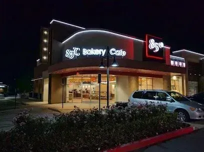tree service close to me-A night view of an 85°C Bakery Cafe, with bright red neon signage and a minivan parked outside.