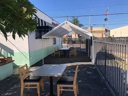 A patio area with tables and chairs under a tent.