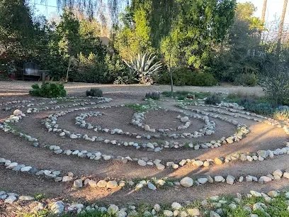 A labyrinth made of rocks in a park with trees in the background.