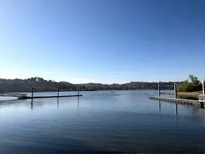 tree service close to me-Calm lake with docks under a clear blue sky, hills in the background.