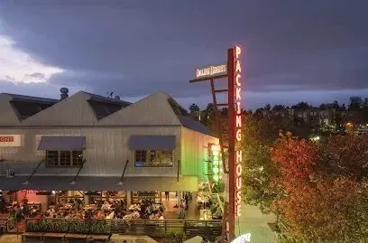 tree service close to me-Packing House building with neon sign at dusk, outdoor dining with people.
