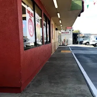 tree service close to me-Exterior of a store with windows displaying ads. Red wall, sidewalk, and street visible.