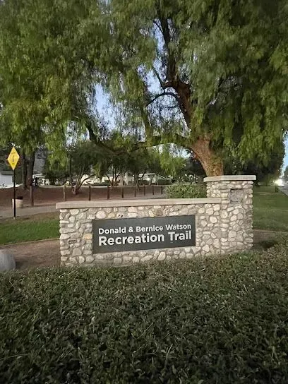 tree service close to me-Sign for the Donald & Bernice Watson Recreation Trail, built with stonework, under a large tree.
