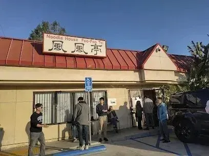 tree service close to me-Exterior of a noodle house with a line of people waiting to enter. Sign above door reads