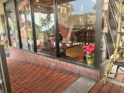 tree service close to me-Restaurant storefront with large windows, brick base, and potted plant.