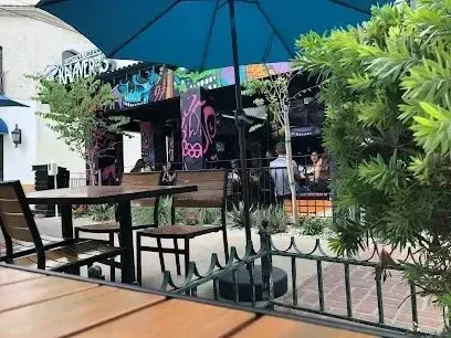 tree service close to me-Outdoor restaurant seating with blue umbrella, tables, and graffiti-covered building.