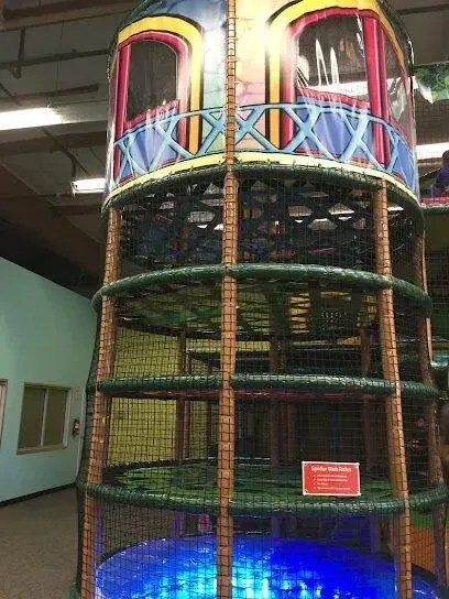 Tree service close to me-Playground with green and yellow structures, a carousel, and wood chip ground under a blue sky.
