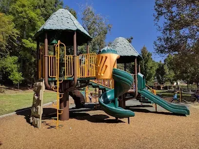 A colorful playground set in a park with trees in the background.