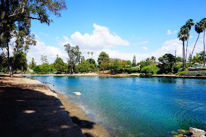 A sunny day at a lake with blue water, trees, and a few clouds.