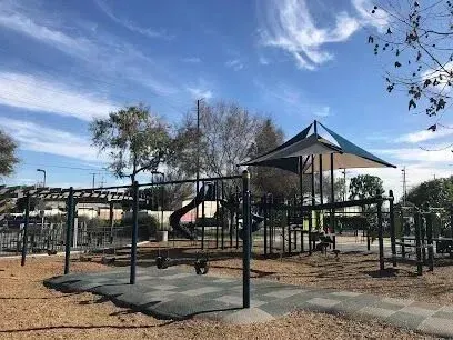 tree service close to me-Playground with slides, swings, and climbing structures under a blue sky.