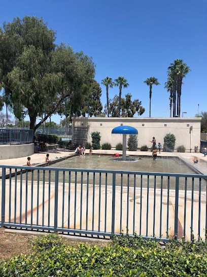 Tree service close to me-Splash pad with train, water tower, and shade structure; blue and colorful.