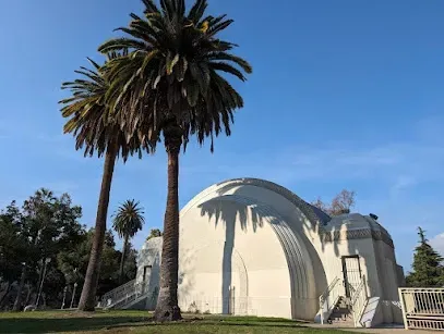 Two palm trees are standing in front of a white building.