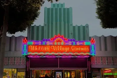 The front of the whittier village cinemas is lit up at night.