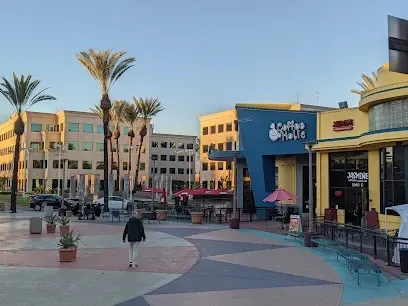 A man is walking in front of a coffee shop in a city.