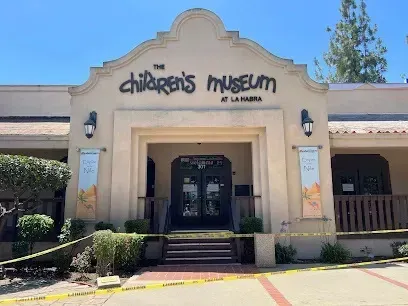 Tree service close to me-The Children's Museum at La Habra building with a tan exterior, arched entrance, and yellow caution tape.